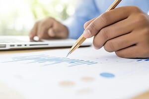 Businessman analyzing data on a printed chart while using a laptop in a minimalist workspace photo