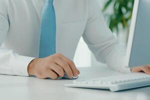 A man dressed in a shirt and tie works on a computer in a bright, minimalist office space during the morning hours photo