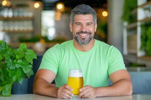 Cheerful man in a green shirt enjoys a refreshing drink in a cozy cafe setting during the afternoon photo