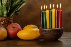 Kwanzaa kinara with all seven candles lit surrounded by fruits and symbolic items on a dark warm background photo