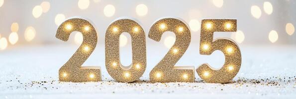 Sparkling golden 2025 displayed on snowy surface with soft lights and glittering confetti for welcoming the new year photo