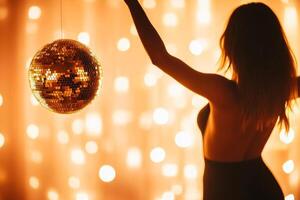 Silhouette holding a glowing disco ball against a warm bokeh background at an evening event photo