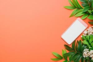 Stylish modern tech device on a warm orange background surrounded by greenery for contemporary advertisements photo