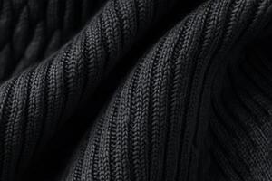 Close-up view of a textured black knitted fabric showcasing intricate patterns on a subtle dark background photo