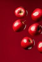 Bright red apples bouncing in mid-air against a vibrant red background showcasing their glossy texture photo