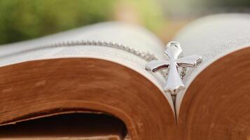 Shiny metal cross leaning against an old open book symbolizing the spread of Jesus Christs love among Christians reflecting faith devotion and the importance of Christian teachings. photo