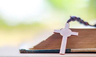 Shiny copper cross leaning against an old open book symbolizing the spread of Jesus Christs love among Christians reflecting faith devotion and the importance of Christian teachings. photo