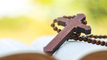 Dark red wooden cross leaning against an old open book symbolizing the spread of Jesus Christs love among Christians reflecting faith devotion and the importance of Christian teachings. photo