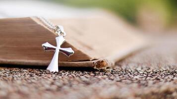 Shiny metal cross leaning against an old open book symbolizing the spread of Jesus Christs love among Christians reflecting faith devotion and the importance of Christian teachings. photo