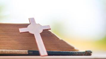 Shiny copper cross leaning against an old open book symbolizing the spread of Jesus Christs love among Christians reflecting faith devotion and the importance of Christian teachings. photo