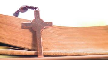 Shiny copper cross leaning against an old open book symbolizing the spread of Jesus Christs love among Christians reflecting faith devotion and the importance of Christian teachings. photo