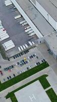 Huge complex and parking places. Roofs of industrial buildings with trucks and car parking in summer. Top aerial view. Vertical video