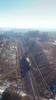 View from above on a freight train. Small cargo train moving on railroad in a sunny winter day. Aerial view. Vertical video