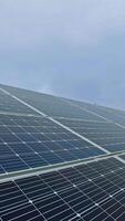 grandes ensolarado bateria em a campo. solar painel produz verde Claro energia a partir de a Sol. arranjo do solar energia Produção plantar. vertical video
