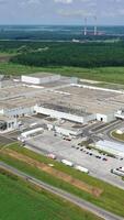 Industrial territory among nature. Huge production plant in the countryside. Modern manufacture on field. Aerial view. Vertical video
