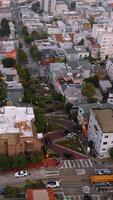 Bright modern dense architecture of San Francisco district. Aerial view on the famous Lombard Street with few cars slowly moving by its curves. Vertical video