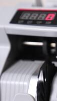 Wad of hundred dollar bills being counted in the banking equipment. Money rotated in machine and then stop. Close up. Vertical video