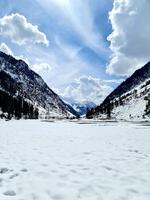 A snowy mountain landscape with a lake and trees photo