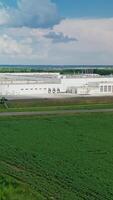 Modern industrial plant in green fields. Large territory of innovative factory among green nature in summer. Aerial view. Camera moves to the right. Vertical video