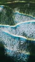 Beautiful relaxing movement of foamy waves on the surface of ocean. Descending drone footage over the deep green waters. Vertical video