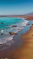 Peaceful mesmerizing view of little waves slowly moving to the sandy shore on sunny day. Scenery of Morro Bay, California, USA from top. Vertical video