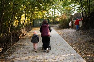 Mother and child strolling through a peaceful autumn forest path photo