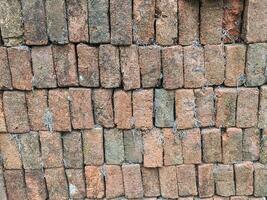 A stack of old, red bricks with a variety of textures and colors, creating a visually interesting backdrop. photo