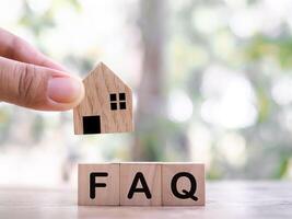 Miniature house, Wooden block with word the FAQ. The concept of question or answer about Property, House, Real estate. photo