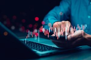 businessman hand type on the laptop of company profit with colleagues partner explain with virtual dashboard statistic chart stock infographic, graphs, cryptocurrency, and new trading platforms photo