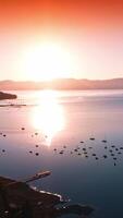 Amazing scenery of Lake Tahoe with numerous boats on. Forest waterfront and sun reflecting in the smooth surface of water. Pink skies at backdrop. Vertical video