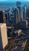 Complicated road systems and junctions between the stunning skyscrapers. Crazy traffic in the downtown of Los Angeles. Aerial view. Vertical video