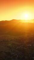 Bright sun setting behind the mountains. Beautiful valley of Napa with lots of cozy houses. Aerial view. Vertical video