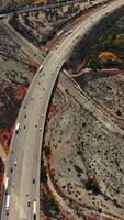 Rocky landscape with some islands of greenery. Multi-lane highway with transport moving by. Top view. Vertical video