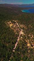 Splendid picturesque panorama of Sierra Nevada mountains covered with pine trees. Amazing Lake Tahoe with boats on it. Top view. Vertical video