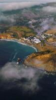 Beautiful rocky coast of sunny Montara State Beach from water. Fog moving on the land from the ocean. Top view. Vertical video