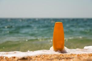 Sunscreen spread out on the beach day. Sunscreen bottle on the sand. Summer, vacation essentials on a sandy beach, ocean in the background. Sun care products photo