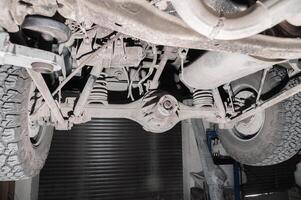 Close-up view from under the car. Dirty suspension of an off-road vehicle. Transmission components photo
