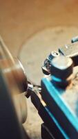 A cutter of lathe is sharpening metal billet for production at the plant. Thin shavings are falling on the surface of the equipment. Close-up. Vertical video
