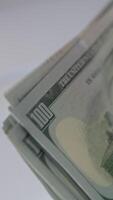 Quickly counted one hundred dollar bills in money counting machine. Rotating mechanism of equipment close up. Blurred backdrop. Vertical video