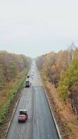 bosque la carretera durante reconstrucción. zumbido ver a lo largo el nuevo asfalto la carretera con especial maquinaria a obras de carretera. cámara se mueve adelante. vertical video