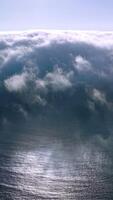 Thick white fog spreading to the coastline from water. Amazing cloudscape of haze on sunny summer day. Aerial view. Vertical video