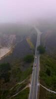 Highway in the mountains with cars running by. Beautiful rocks of Montara, California, USA. Horizon in thick fog. Vertical video