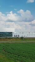 Industrial area among natural environment. Huge territory of manufacturing complex on green field under beautiful summer sky. Front view. Vertical video
