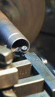 A metal part rotates and sharpeners on the lathe in the workshop in the manufacturing. Close-up. Vertical video