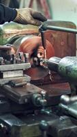 A worker controls the process of drilling a hole in a part on a lathe using coolant for cleanliness processing of surface. Close-up. Vertical video