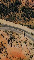 Highways in the mountains. Rocky landscape with sparse pine trees. Sunny scenery of Arches canyons from top view. Vertical video