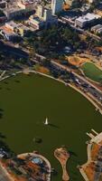 Pond with fountain in the middle in the park. Circling around the green area in Los Angeles, California, USA from top. Vertical video