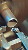 A metal shavings are falling to the floor during processing of part on the lathe in the production. Close-up. Vertical video