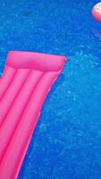 Swimming circle and inflatable mattress on the water surface. Swimming appliances in the pool with no people in. View from top. Vertical video