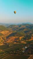 Hot air balloons soaring over the rock formations in Napa, California, USA. Sunny scenery at the backdrop of blue skies. Vertical video